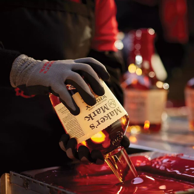 A bottle of Makers Mark being dipped into red wax