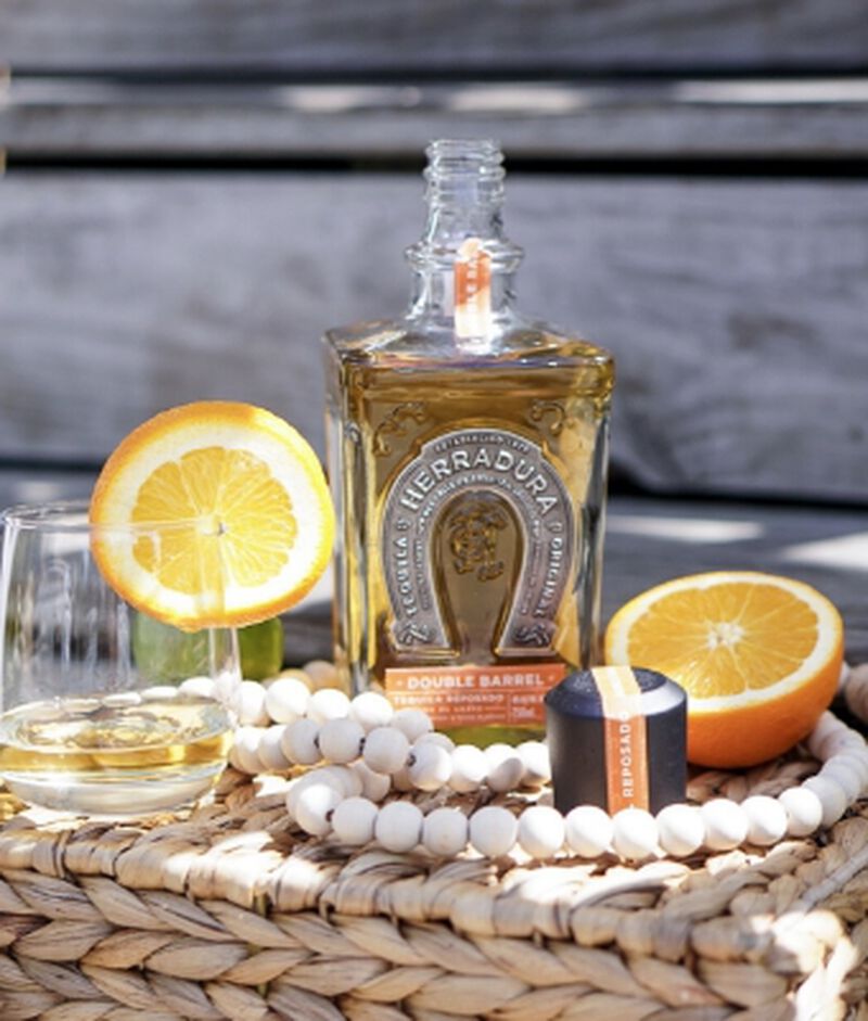 Bottle of Tequila Herradura Double Barrel Reposado S1B58 with a glass and citrus outside